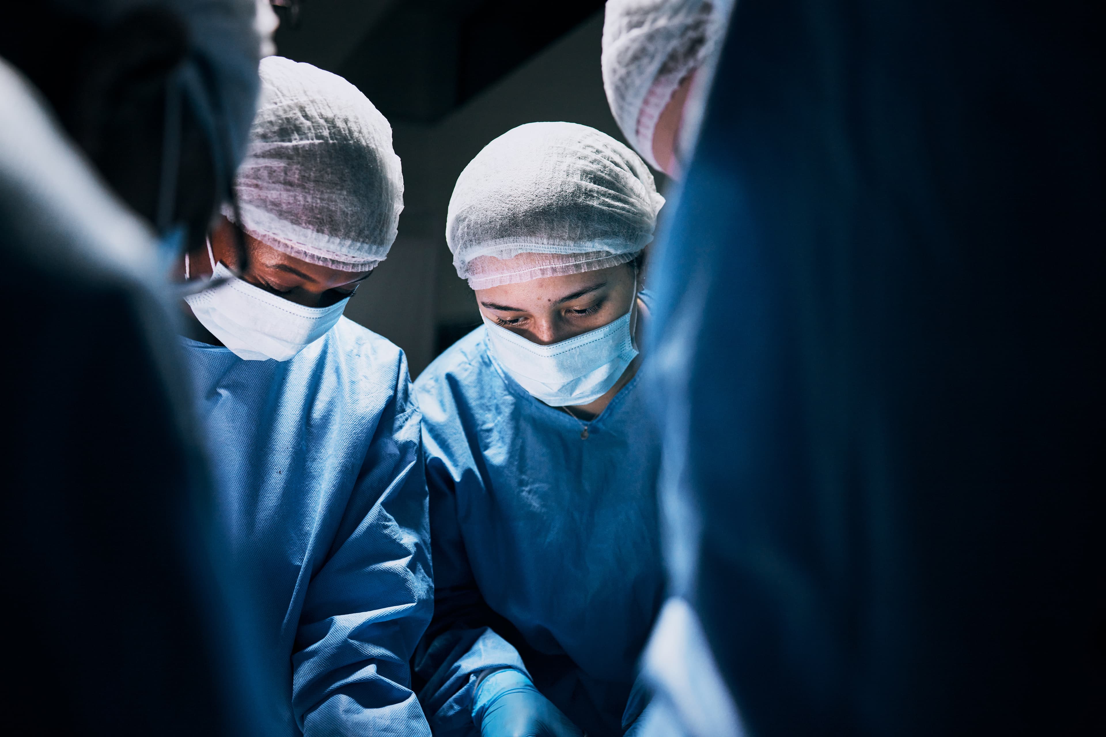 Surgeons in deep-blue scrubs focused during a procedure